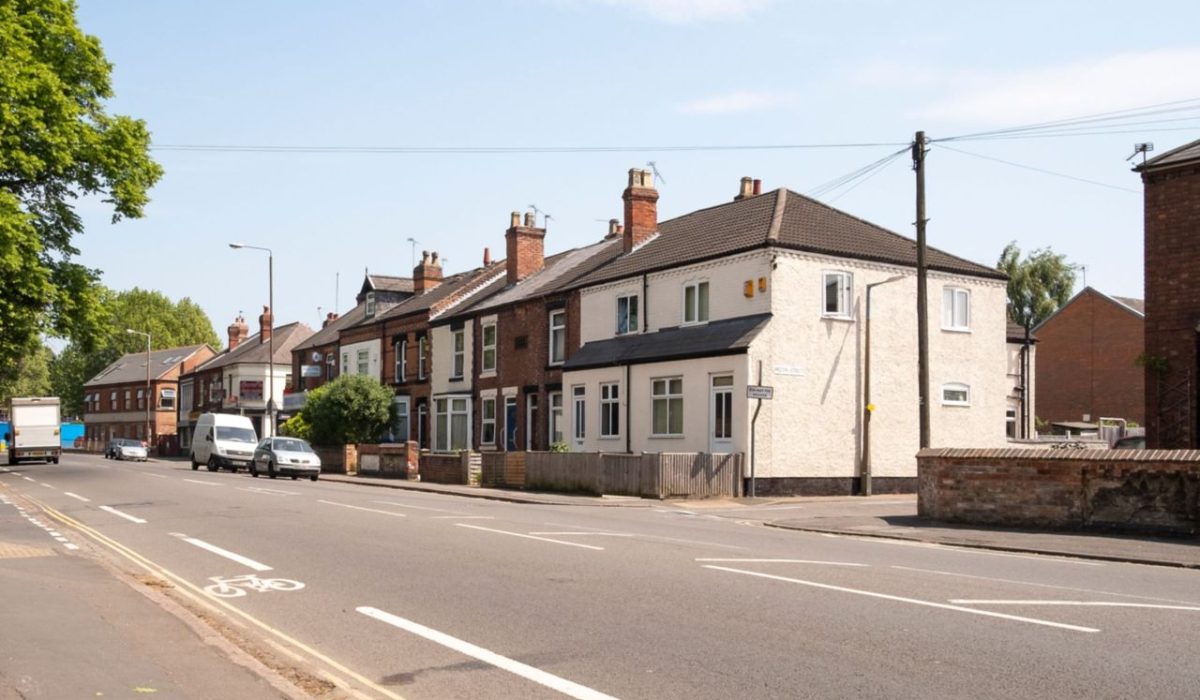 A row of red-brick terraced houses on a Manchester street on a sunny day